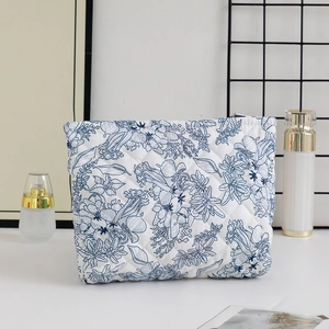 Close-up of quilted floral cosmetic bag with blue plant print and metal zipper closure