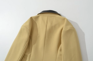 Detail of beige jacket showing black collar stitching and shoulder seam construction