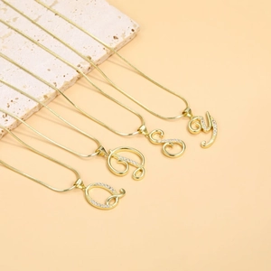 Close-up of gold snake chain necklaces with zircon-studded initial pendants Q D S Y