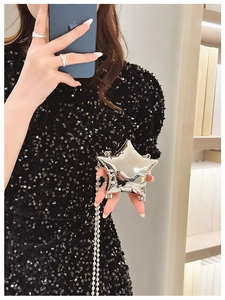 Detail of silver star-shaped mini crossbody bag with bead chain on black sequin dress