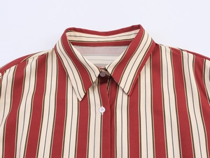 Détail du col d'une chemise à rayures rouges et beige avec boutons blancs et couture fine