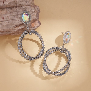 Macro detail of silver beaded hoop earrings with iridescent oval crystal stones