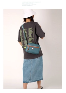 Blue nylon crossbody bag with wide strap worn by a model in a minimal studio setting