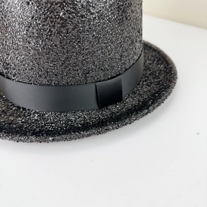 Gros plan détaillé sur la texture pailletée du chapeau noir avec ruban de gros-grain