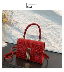 Close-up of red crocodile-embossed handbag with golden H-clasp and leather top handle