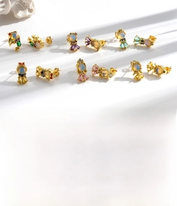 Detailed macro shot of fishtail stud earrings featuring colorful cubic zirconia on gold base