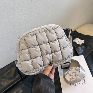 Detail of beige quilted puff fanny pack with adjustable strap and textured nylon surface