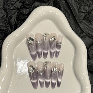 Close-up of luxury purple cat-eye press-on nails with rhinestones and metal chains