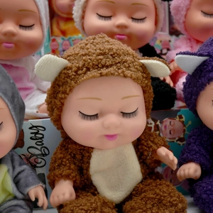 Close-up of realistic 8-inch sleeping baby dolls in soft brown bear plush outfits