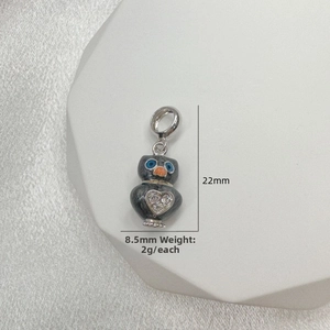 Macro shot of silver owl charm with enamel detail, heart crystal, and 22mm x 8.5mm dimensions