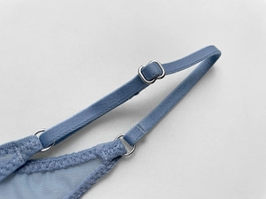 Detail of adjustable blue lingerie strap with silver metal buckle and sheer mesh fabric