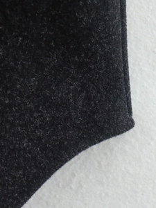 Gros plan sur la texture du tissu en laine noire et coutures détaillées de la veste