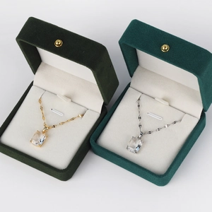 Gold and silver cross necklaces with emerald square pendants in a velvet gift box