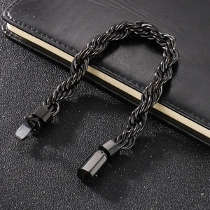 Dettaglio di un bracciale a catena a spirale nero in acciaio su un taccuino ruvido