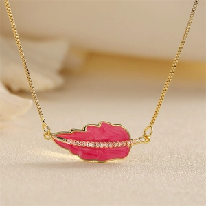 Macro detail of gold-plated box chain and pink enamel leaf pendant with sparkling gems