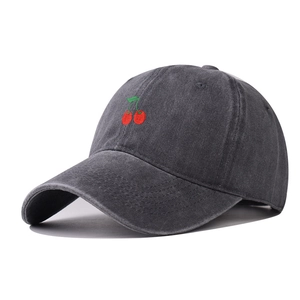Close-up of small red cherry embroidery on a vintage washed dark grey baseball cap