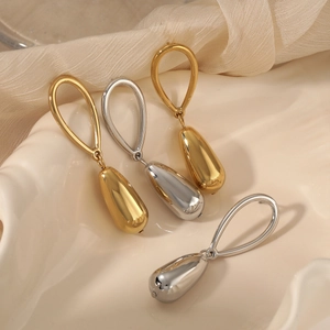 Exaggerated stainless steel water drop earrings in gold and silver finish set on a tray