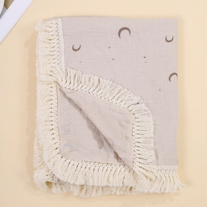 Close-up of cotton baby blanket with star moon prints and delicate white tassel trim