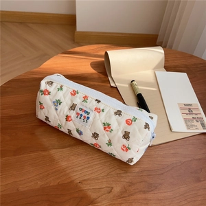 Detailed close-up of quilted floral pencil case with bear pattern on wooden desk