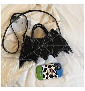 Detail of bat-shaped black crossbody bag with white spiderweb stitching and dual handles