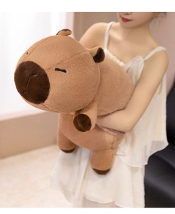 Close-up of a large soft capybara plush toy being held, showing its brown fluffy texture