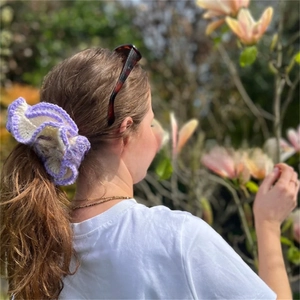 Close-up of a handmade crochet ruffled hair scrunchie in purple and white yarn colors