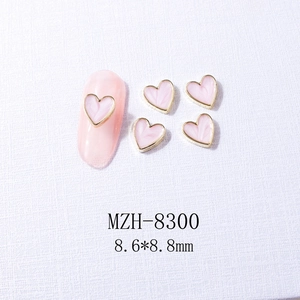 Detail view of 8.6x8.8mm pink marble heart nail charms with golden metal edges