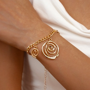 Detail of gold chain bracelet featuring twin spiral rose pendants on a model's wrist