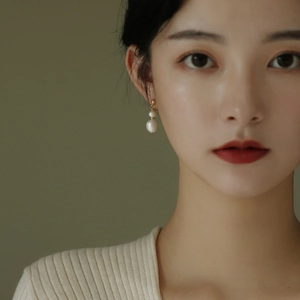 Elegant gold earrings with double freshwater pearls shown on a model's ear