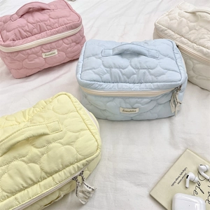 Detailed view of four colorful quilted cosmetic bags with soft cloud stitching and handles