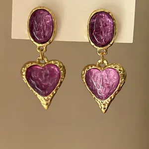 Detail of vintage heart drop earrings with purple textured resin and gold hammered frame