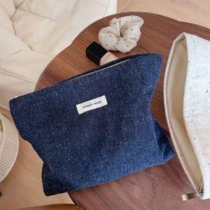Detail of blue denim cosmetic bag with colorful speckles and simple wish label on desk