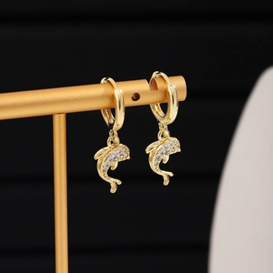 Close-up of golden dolphin earrings featuring crystal pavé back on a jewelry stand
