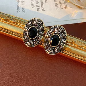 Orecchini vintage dorati con pietra ovale nera e micro-cristalli su fondo in pelle