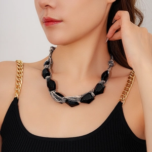 Close-up of geometric black faceted beads and mixed metal chain necklace on a model
