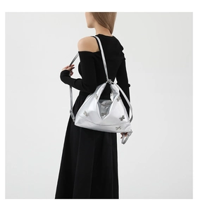 Detail of silver metallic shoulder bag with 3D bow accents worn with black outfit