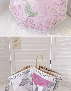 Detail of pink floral umbrella with golden J-handle and elegant rose patterns