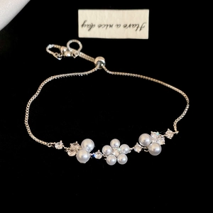 Detail of luxury zircon flower pearl bracelet with silver-tone chain on black velvet