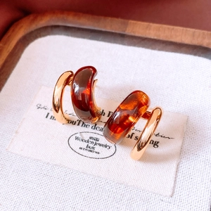 Detailed close-up of double-layer C-shape gold and amber resin hoop earrings