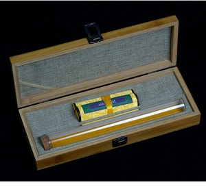 Detailed view of bamboo incense gift box with agarwood scroll and glass tube on black background