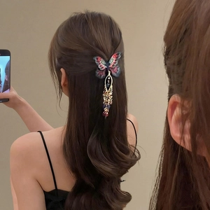 Détail d'une pince à cheveux papillon tricotée avec perles et pompons sur modèle
