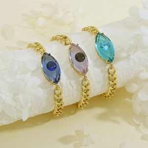 Detail eines Evil-Eye-Kristallarmbands mit Goldkette in Blau- und Lilatönen