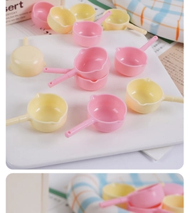 Close-up of pink and yellow miniature dollhouse pans on a cozy checkered fabric background