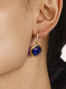 Gros plan détaillé des boucles d'oreilles en verre bleu saphir doré sur un mannequin