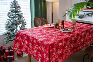 Close-up of red Christmas tablecloth featuring white snowflake prints and holiday decor