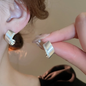 Detail of matte silver C-shaped hoop earrings featuring micro-set zircon stone inlay