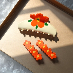 Ensemble pince à cheveux et barrettes avec fleurs orange sur plateau doré