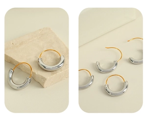 Close-up of two-tone geometric hoop earrings in polished silver and 18K gold finish