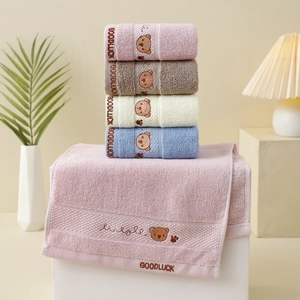 Detail of four colorful cotton towels with bear embroidery stacked on a white stand
