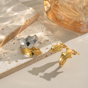 Polished gold and silver seaweed leaf rings on marble slab with aesthetic shadows